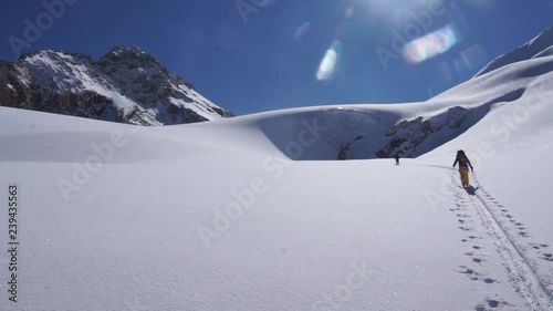 Backcountry skiers ascending towards glacial ice cave photo