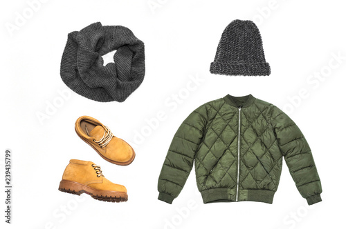 Winter jacket green, yellow boots with a tractor sole, gray woolen hat and scarf on a white background. Flat lay. Winter look