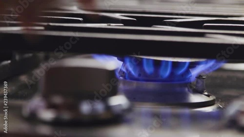 Close up of hand turning on, then turning off gas stove, with blue flame photo