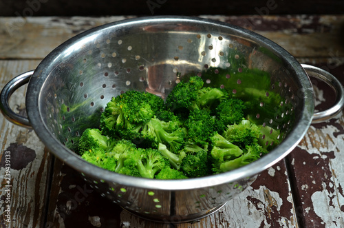 Freshly washed pieces of broccoli in a metal colander