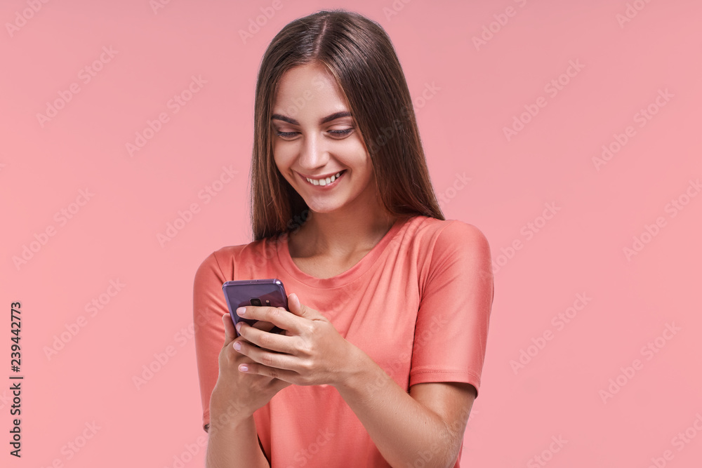 Excited female model received unexpected message or news on smartphone, looks joyful into smartphone, has overjoyed expression. Positive young joyful woman views funny photos on mobile phone. Excited female model received unexpected message or news on smartphone, looks joyful into smartphone, has overjoyed expression. Positive young joyful woman views funny photos on mobile phone.