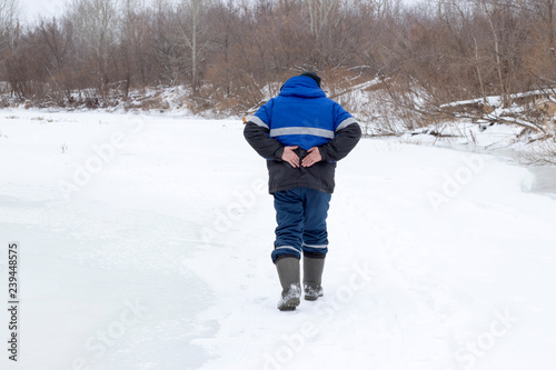 A man walks in the winter and holds on to his back, a beautiful winter nature.