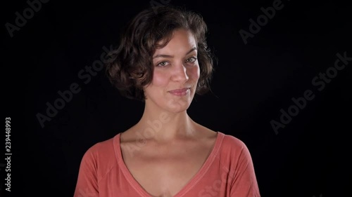 Close up shot of an attractive young woman, isolated on a black background. Her expression, looking at the camera, suggests flirtatious skepticism, or friendly doubt photo