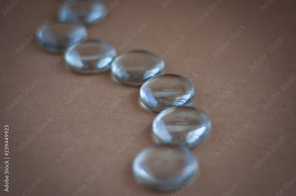 Clear marbles with light reflections on a brown background. Clear marbles with light reflections on a brown background.