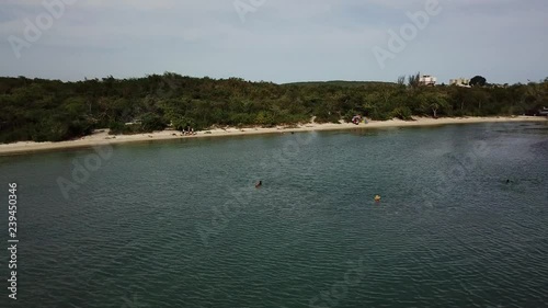 AERIAL: camera sweep showing a bay with aqua colored water and some people enjoying inside the ocean photo