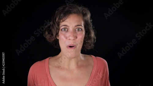 Medium close-up of an attractive young woman, isolated on a black background, looking at the camera with wide eyes and expressing her giddy excitement photo