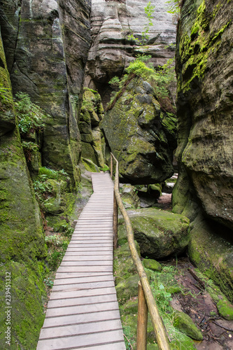 Wooden trail between rocks with wooden railing.