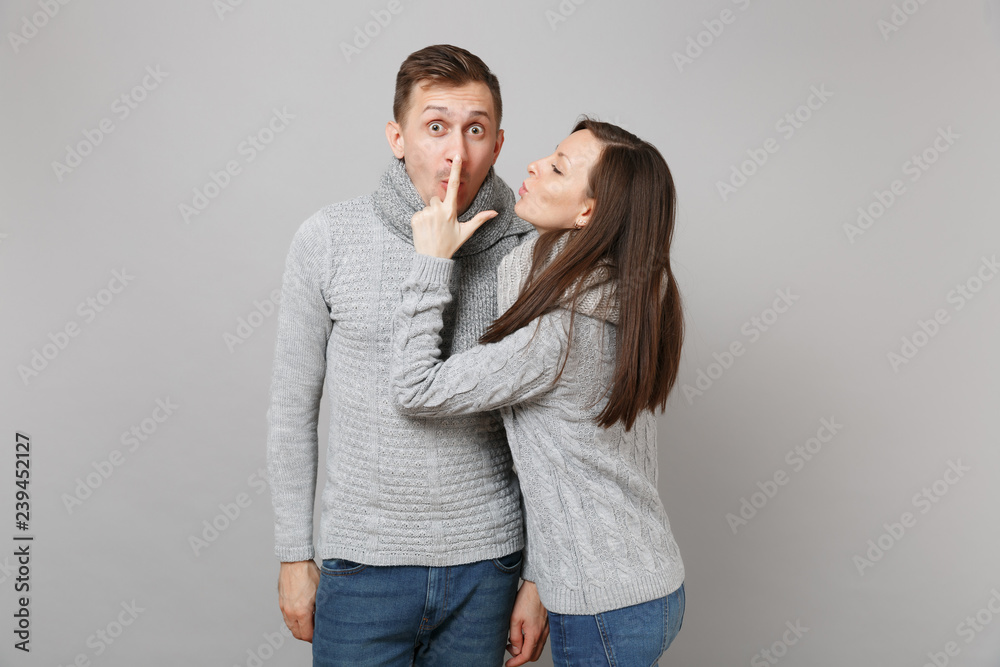 Young cute couple girl guy in gray sweaters, scarves together isolated on grey wall background, studio portrait. Healthy lifestyle, ill sick disease treatment, cold season concept. Mock up copy space.