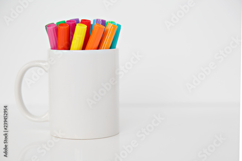 colorful pens in cup on white background