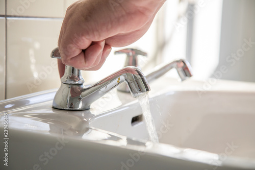 Mann nutzt Waschbecken mit Leitungswasser zum Händewaschen