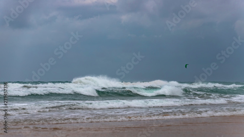 Surfer's parachute in a stormy sky over the foamy waves of the Mediterranean Sea. Israel