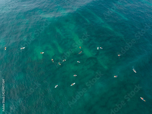Photography Aerial view from drone of surfers paddling for catching waves during surfing  in