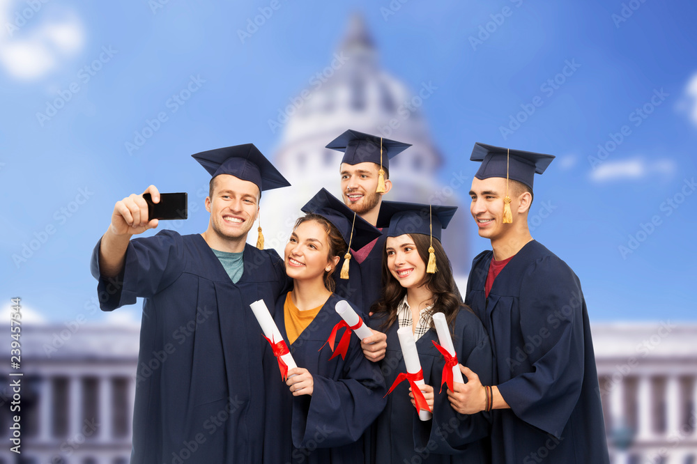 education, graduation and people concept - group of happy graduate students in mortar boards and bachelor gowns with diplomas taking selfie by smartphone over washington white house background education, graduation and people concept - group of happy graduate students in mortar boards and bachelor gowns with diplomas taking selfie by smartphone over washington white house background