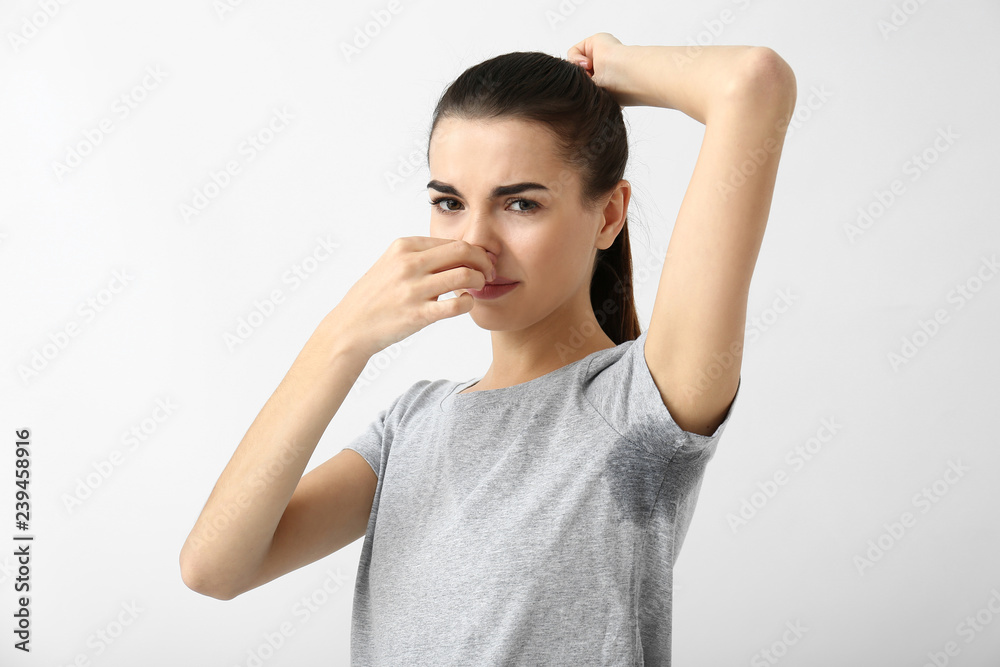 Beautiful young woman feeling smell of sweat on white background. Concept of using deodorant