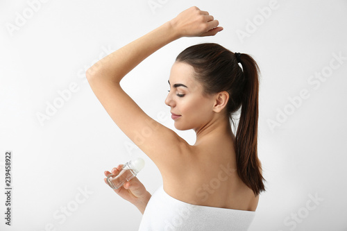Young woman using deodorant...