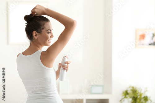 Young woman using deodorant at home photo