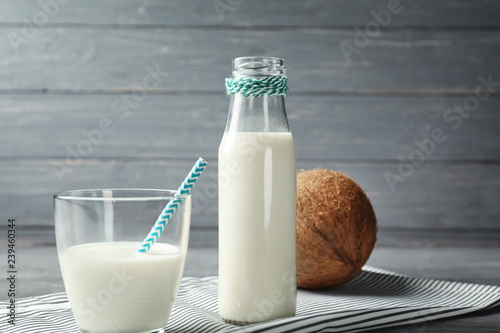 Glass and bottle of tasty coconut milk on table