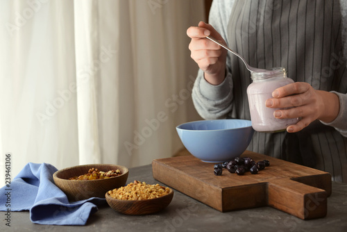 Woman preparing tasty granola in kitchen