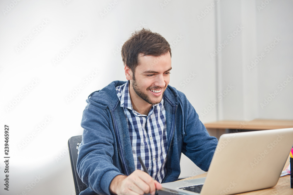 Junger Mann als Informatiker am Laptop PC