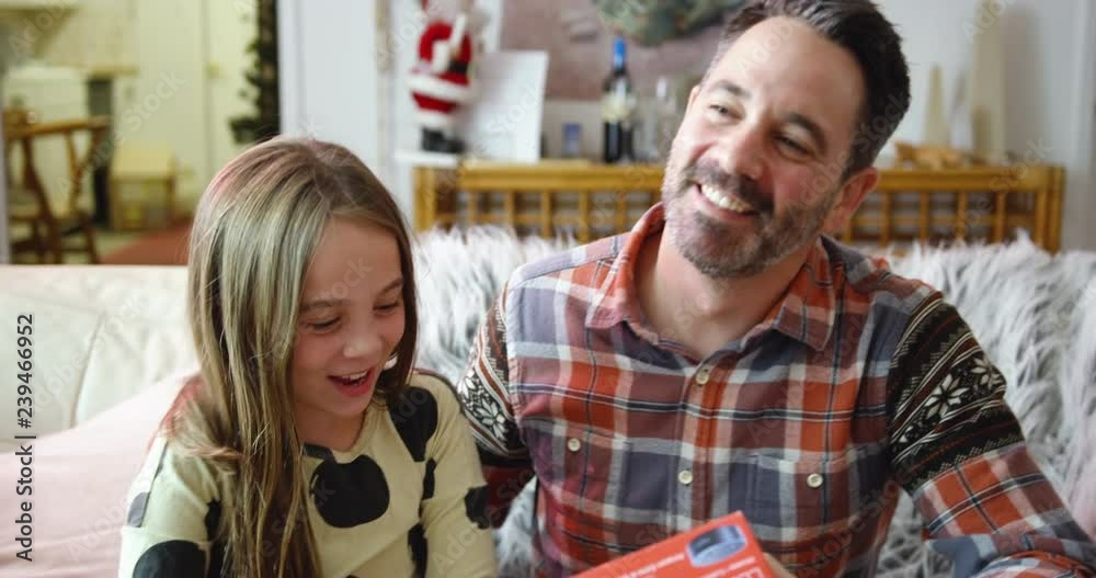 Dad gives his little girl a kiss on the head after she gives him a Christmas gift.