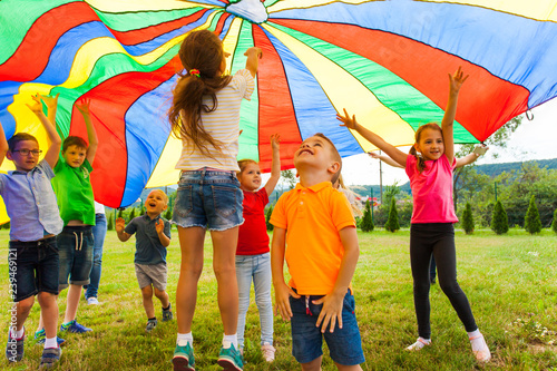 Overjoyed kids bouncing under rainbow canopy textile