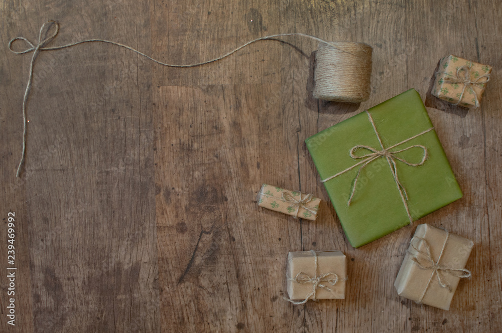 Christmas composition present boxes wrapped in green and sandy kraft paper with kraft rope on wooden background. Flat lay style, top view, copy space. Christmas composition present boxes wrapped in green and sandy kraft paper with kraft rope on wooden background. Flat lay style, top view, copy space.