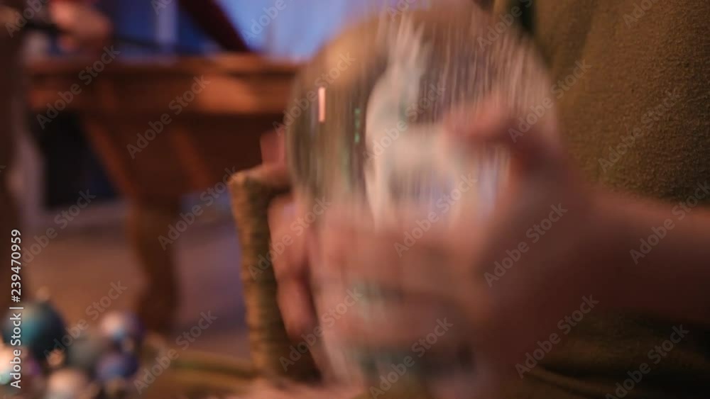 Close up of girl shaking snow globe at a holiday party.