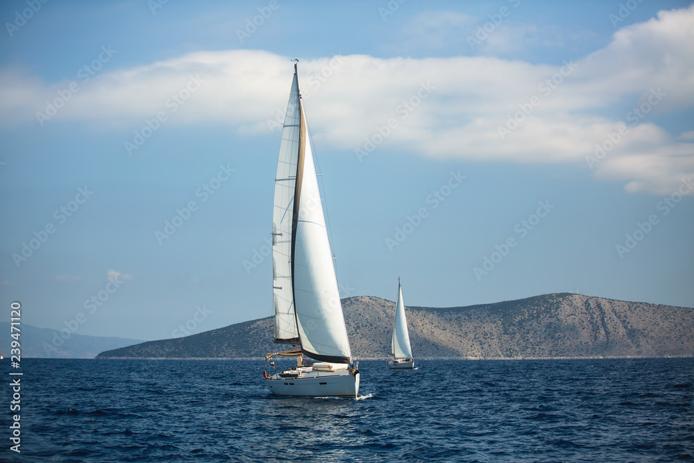 Sailing luxury yacht boats glide on the water surface of the Aegean Sea, Greece.