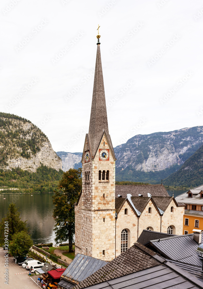 Hallstatt church vertical photo with Alpine mountains on background.