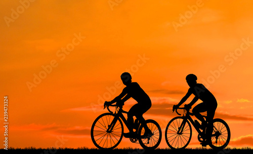 Silhouette group friend and bike relaxing on blurry sunset background