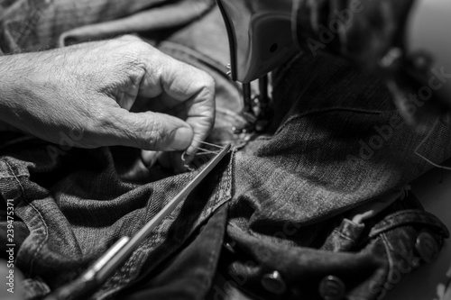 Closeup hands of Tailor man working on old sewing machine. jeans cloth fabric textile in shop, Tailoring, close up.