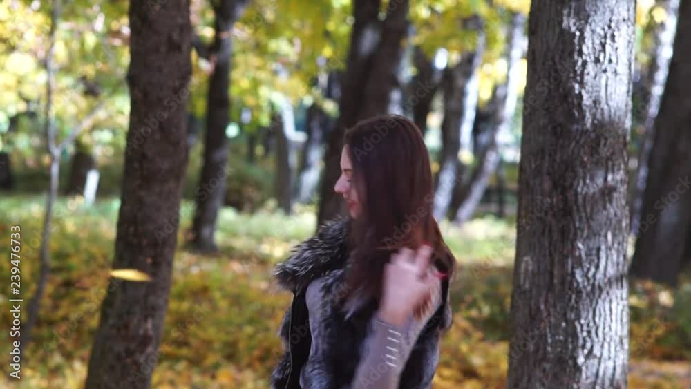The girl throws leaves in the autumn park. The woman is having fun. The girl throws leaves in the autumn park. The woman is having fun.