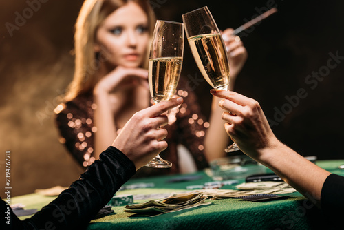 Photography selective focus of attractive girls clinking with glasses of champagne at poker