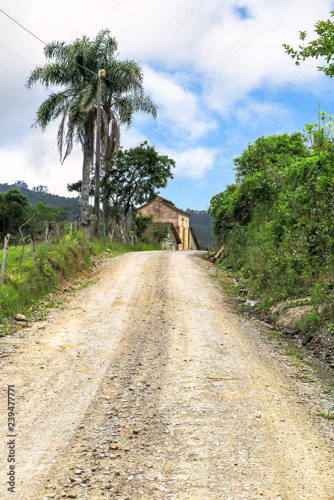 Rise on dirt road, with barn in the background, blue sky with clouds, Presidente Nereu, Santa Catarina