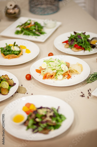 Meat, fish, salads on the table in white plate in the interior with olive oil