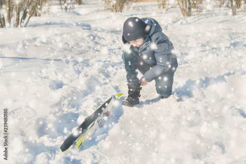 Teen boy on skis in the park in the winter snowfall.