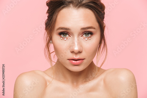 Beautiful young woman posing isolated over pink wall background.