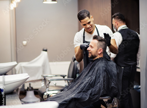 A man client visiting haidresser and hairstylist in barber shop.