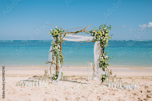 Fototapeta Naklejka Na Ścianę i Meble -  Wedding arch with white flowers at blue ocean in tropical island. Wedding ceremony.