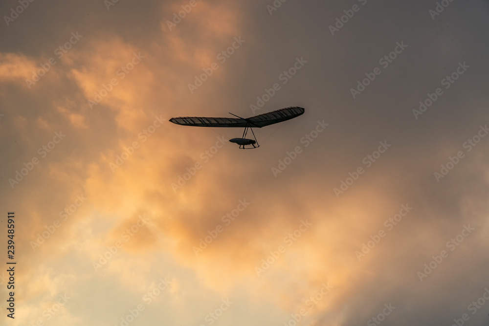 Hang glider pilot fly over dramatic sunset sky Hang glider pilot fly over dramatic sunset sky