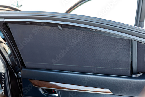 Sunblind on the glass of the rear door of the car black color close-up protects from the sun rays textured double mesh of a special material. © Aleksandr Kondratov