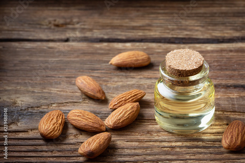 Almond oil in bottle and nuts on wooden table