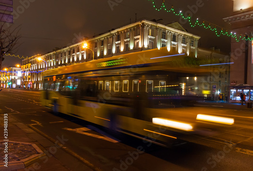 The motion of a blurred bus on the avenue in the evening.