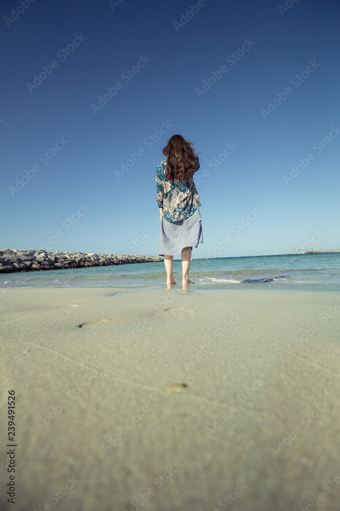 brunette walking on a sandy beach