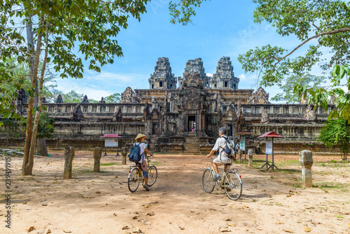 Tourist couple cycling around Angkor temple, Cambodia. Ta Keo building ruins in the jungle. Eco friendly tourism traveling. © fabio lamanna