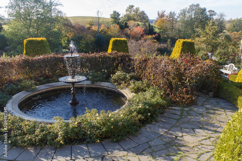 Fountain in park  with topiary and stone pavement.