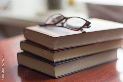 a stack of several books and glasses on the table