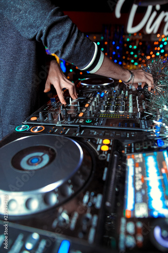 Dj mixes the track in the nightclub at party. In the background laser light show