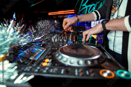 Dj mixes the track in the nightclub at party. In the background laser light show