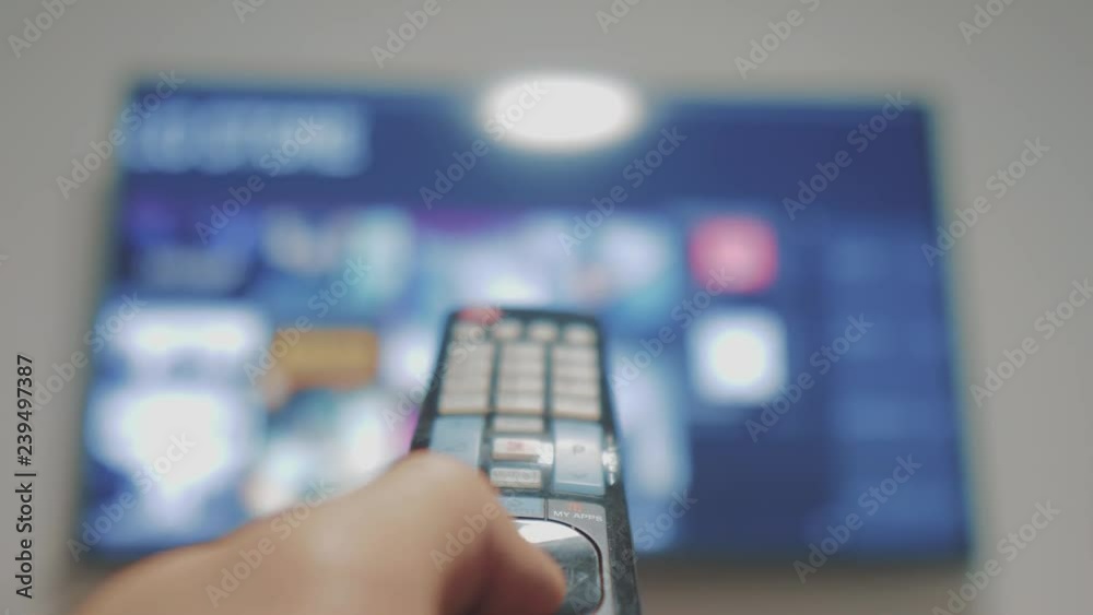 Smart tv with apps and hand. Male hand holding the remote control turn off smart tv. man hand controls TV holding remote. lifestyle concept internet online cinema Smart tv with apps and hand. Male hand holding the remote control turn off smart tv. man hand controls TV holding remote. lifestyle concept internet online cinema